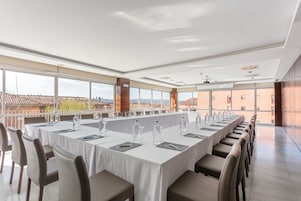 Un salón de conferencias con una larga mesa, sillas y botellas de agua.