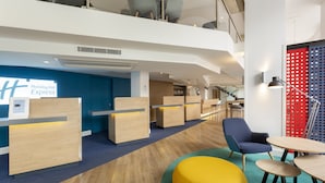 A hotel lobby with a reception desk, seating area, and a staircase.