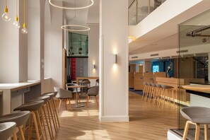 Un interior moderno con suelo de madera, una zona de bar y diferentes disposiciones de asientos.
