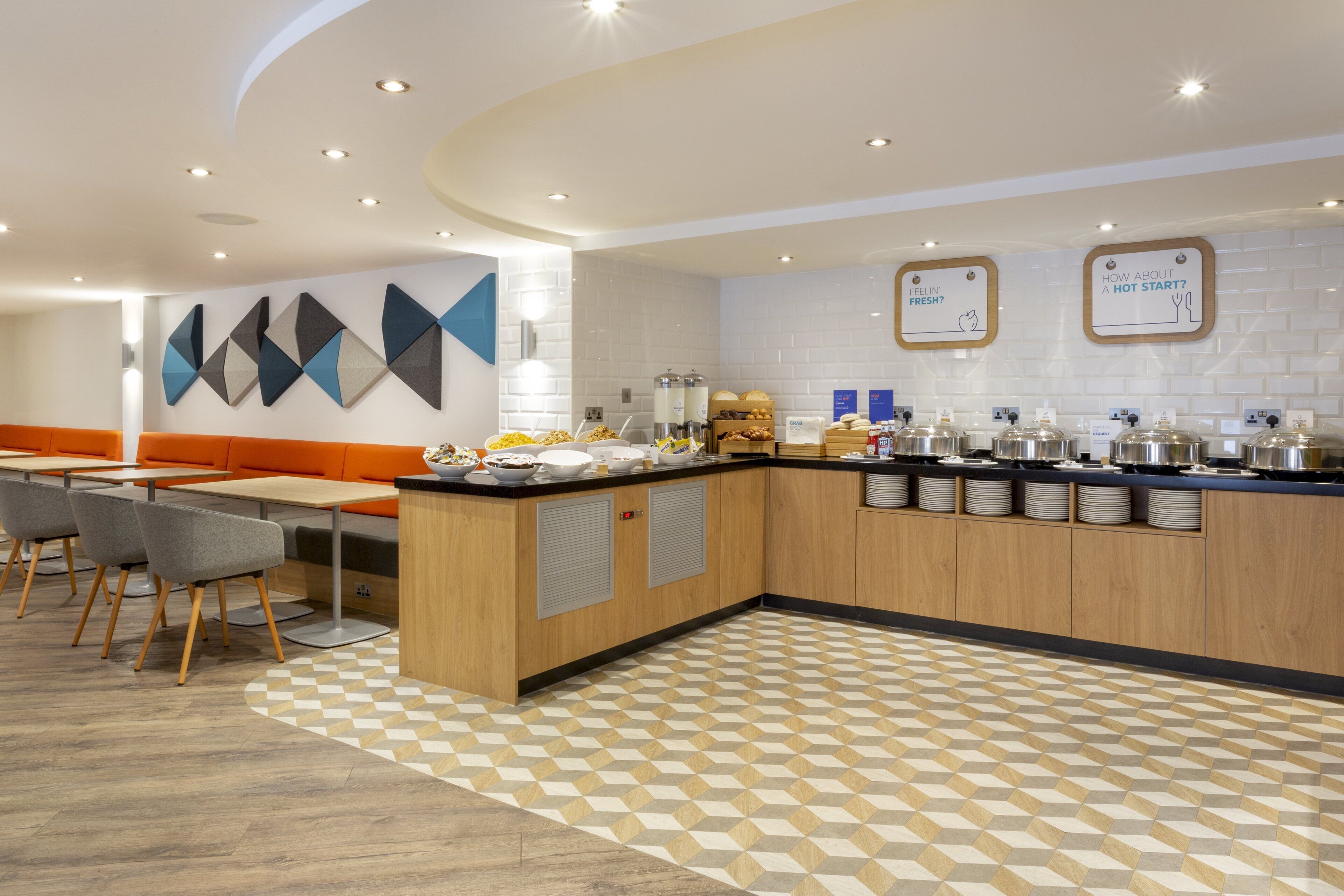 A modern kitchen area with a breakfast bar, seating, and a patterned floor.