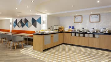A modern kitchen area with a breakfast bar, seating, and a patterned floor.