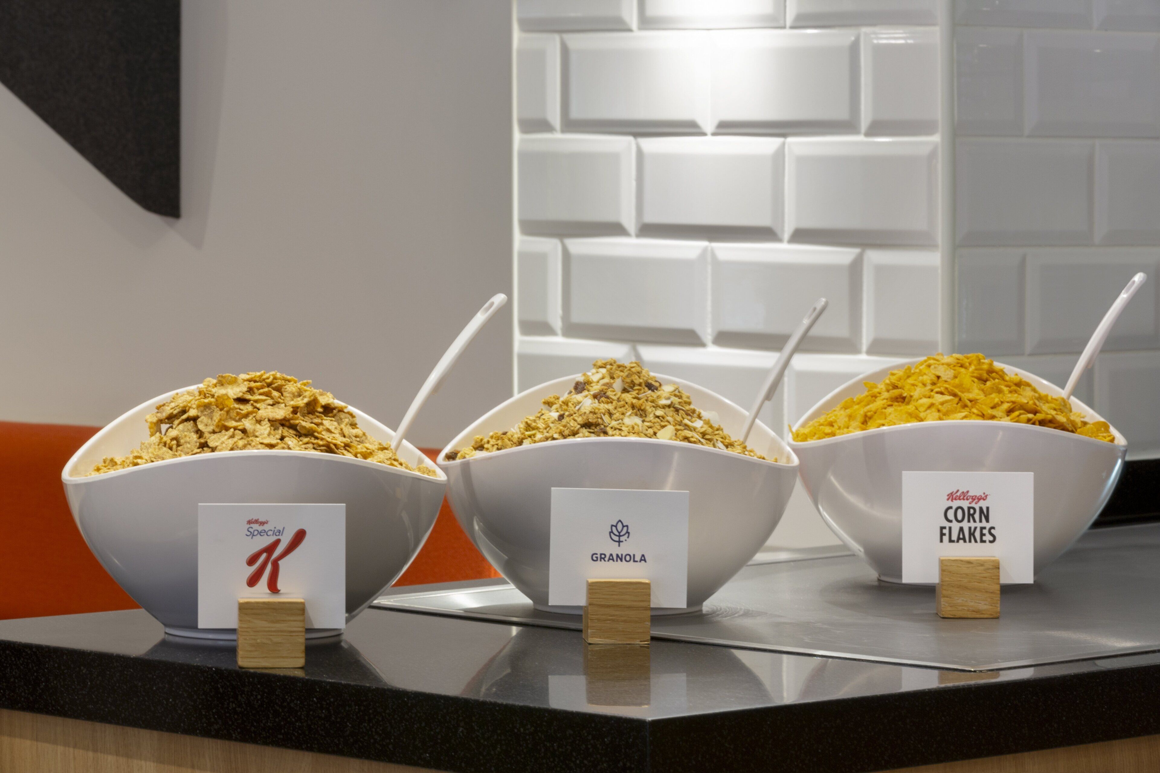 Three bowls of cereal on a countertop with labels indicating different brands and flavors.