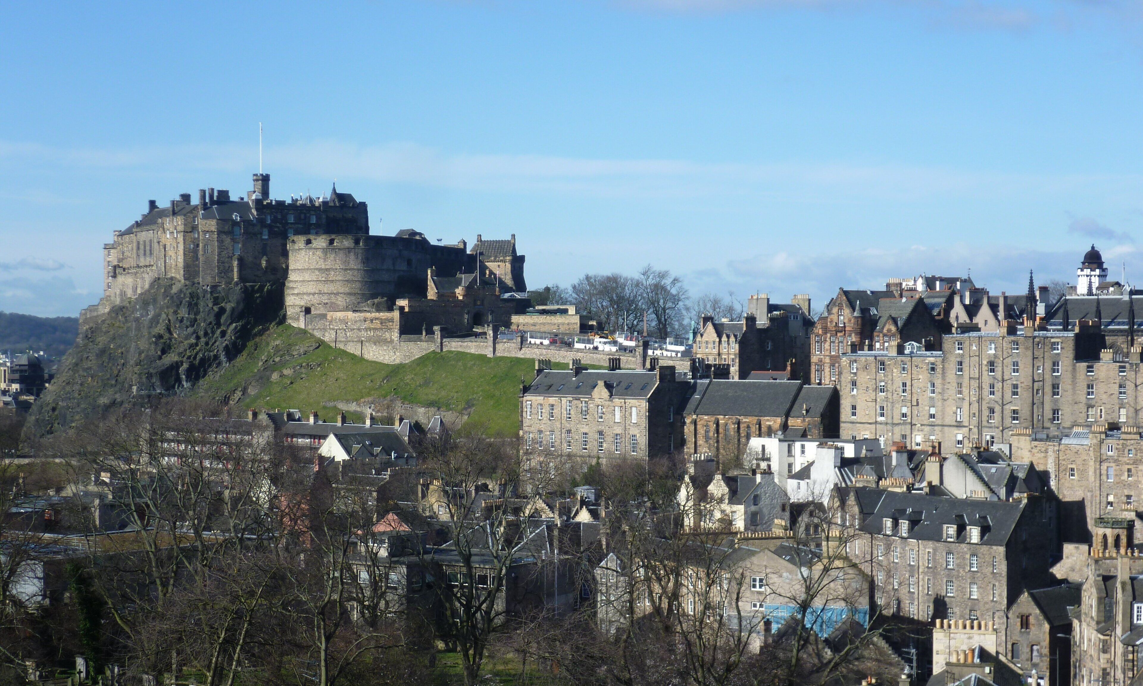 A historic castle on a hill overlooking a city with traditional stone buildings.