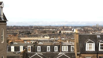 A cityscape with a mix of residential and commercial buildings, including a prominent stone building with a pitched roof and dormer windows.