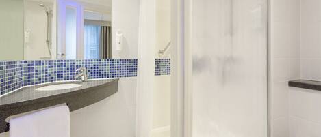 Un baño moderno con ducha acristalada, lavamanos con salpicadero de azulejos azules y inodoro blanco.