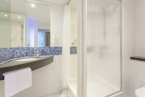 A modern bathroom with a glass-enclosed shower, a sink with a blue-tiled backsplash, and a white toilet. - Holiday Inn Express - Edinburgh City Centre by IHG (Edinburgh)