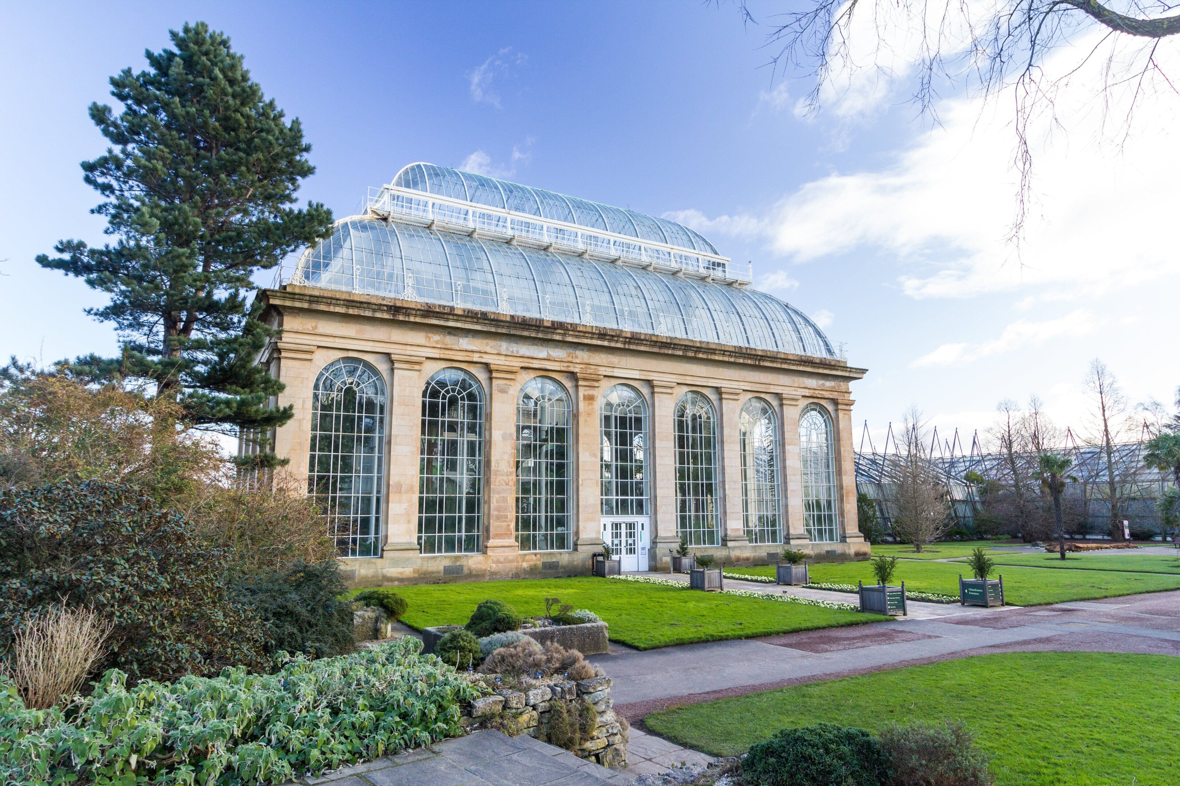 A large glass-domed building with multiple arched windows, surrounded by well-maintained lawns and trees.