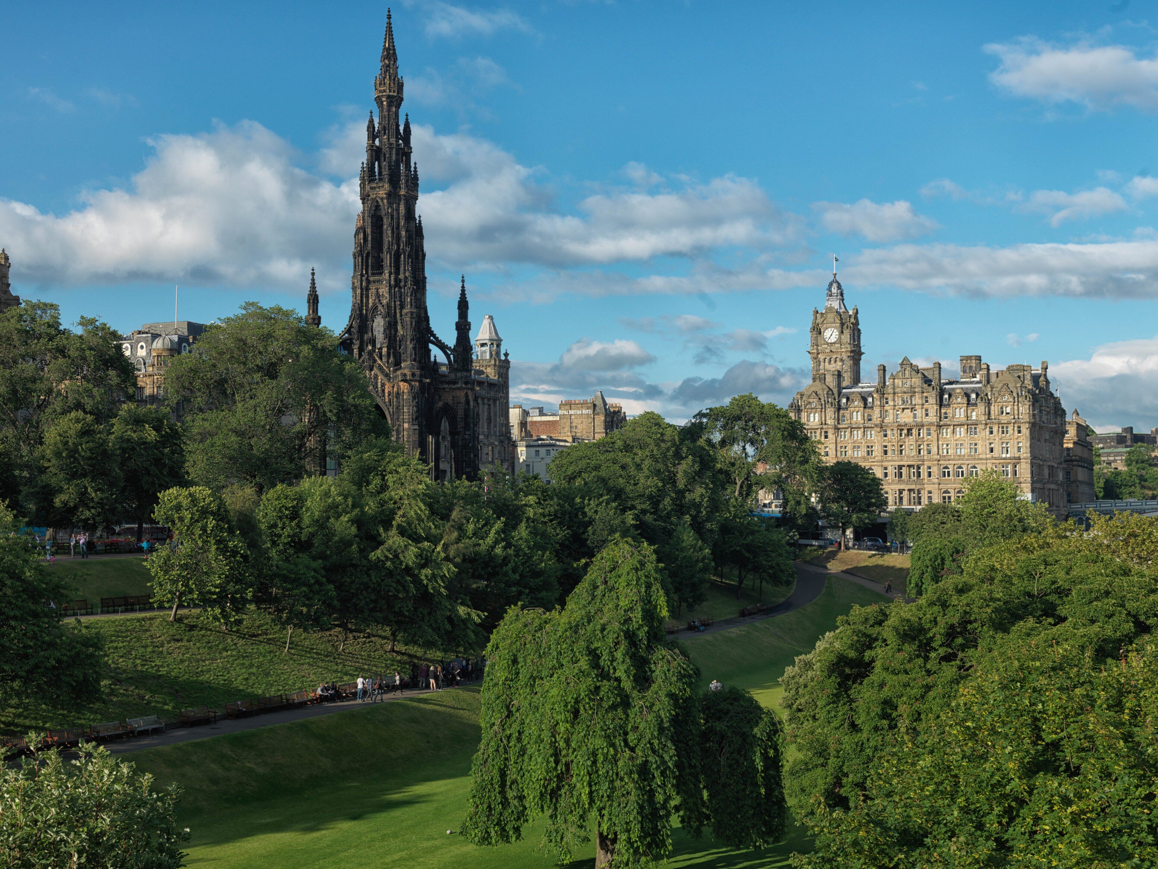 A historic building with intricate architecture, surrounded by lush greenery and a clear sky.