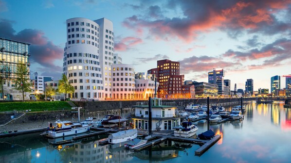Eine Marina mit vertäuten Booten, umgeben von modernen Gebäuden mit markanter Architektur.