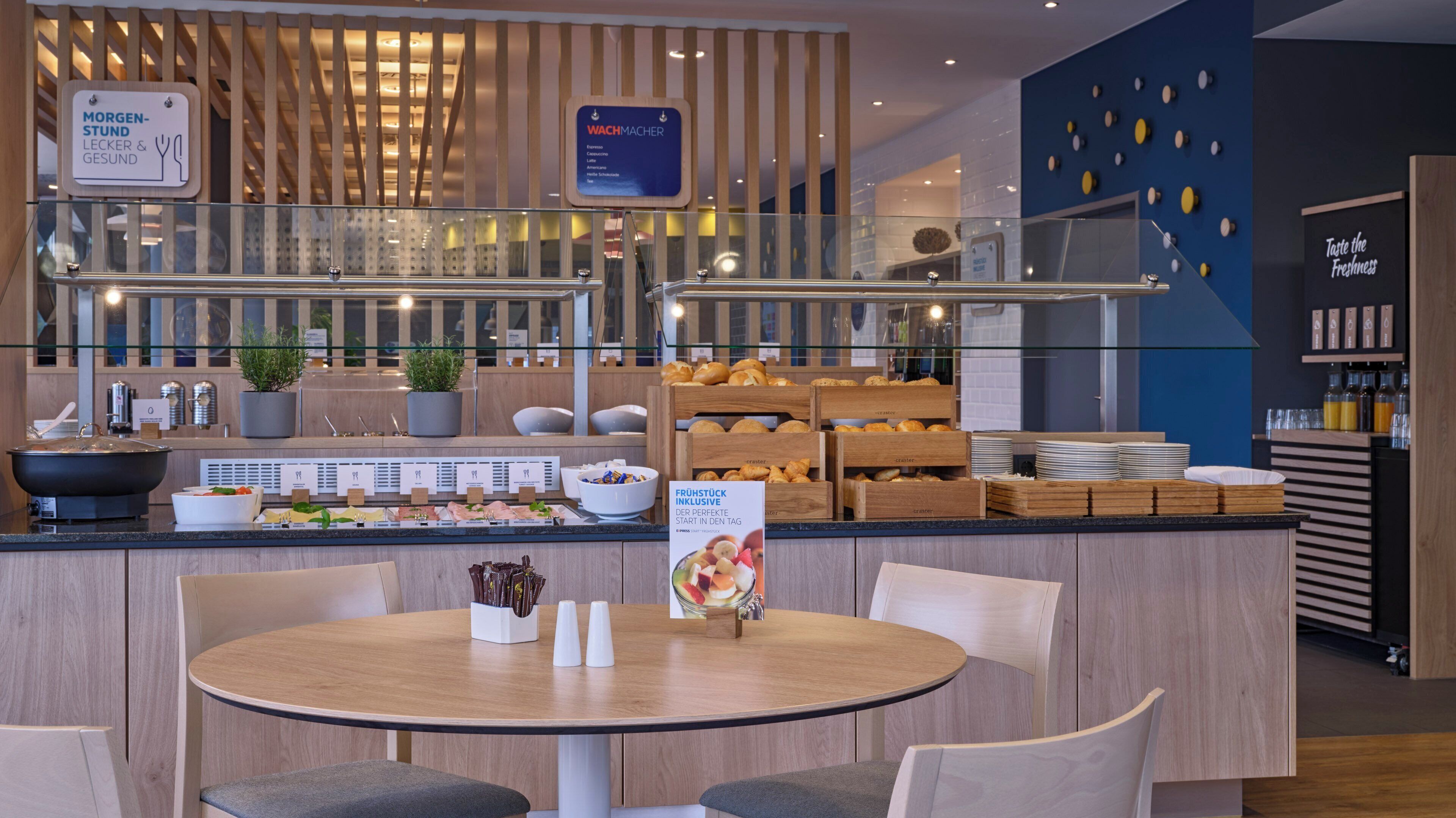 Un buffet pour le petit-déjeuner proposant une variété d’aliments, notamment des viennoiseries et des fruits, ainsi qu’un panneau indiquant un point de vente proposant des options pour le petit-déjeuner et des produits axés sur la santé.