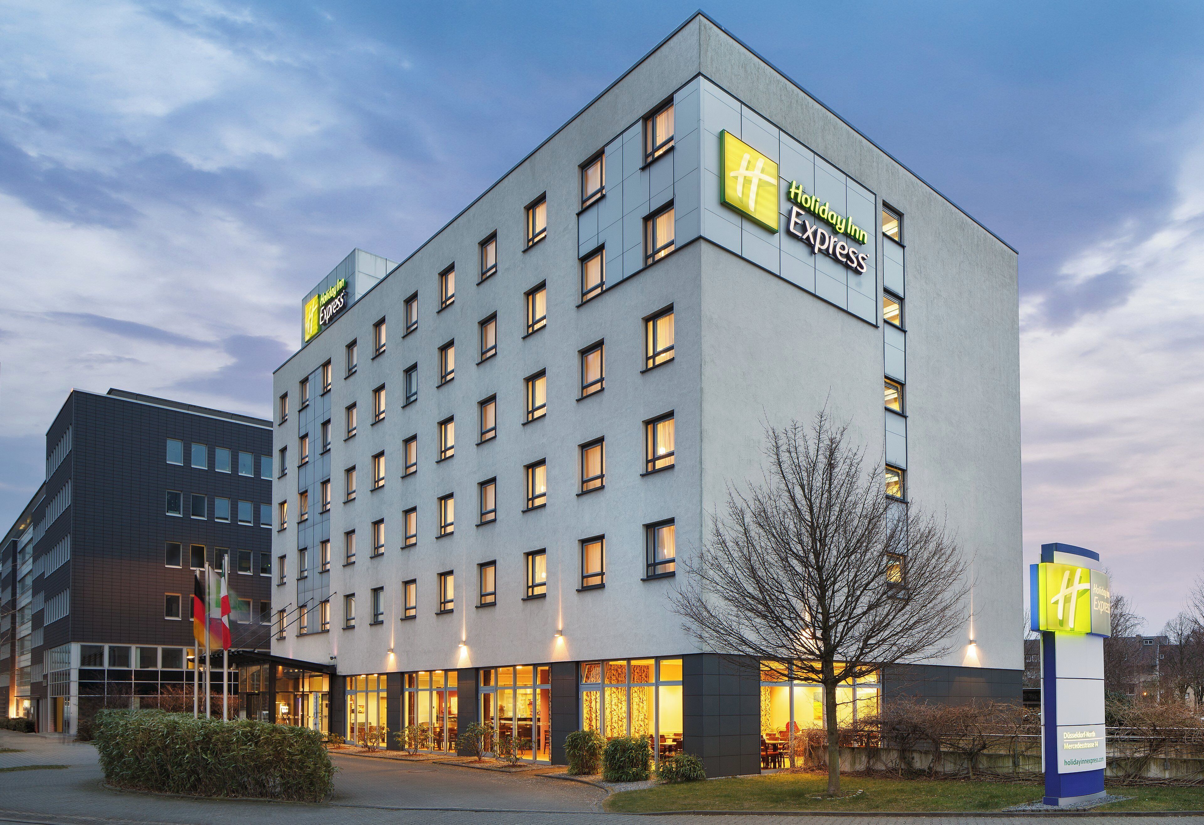Un hotel Holiday Inn Express con diseño moderno, varios pisos y una fachada bien iluminada.