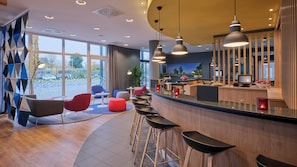 A modern bar area with a curved counter, multiple stools, and pendant lighting.