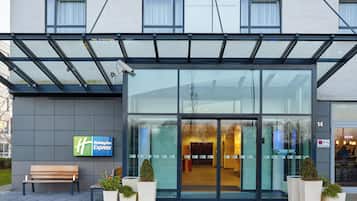 A Holiday Inn Express building with a glass entrance, outdoor seating, and potted plants.