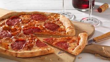 Eine Pizza auf einem Holzboden, mit einem Messer, einem Weinglas und einer Weinflasche.