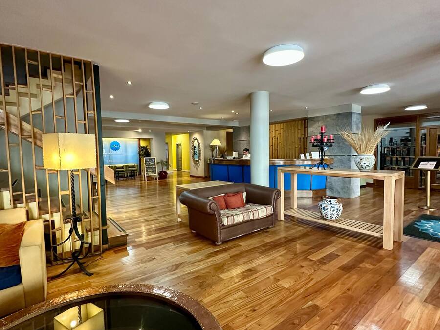 Um hall amplo com piso de madeira, balcão de recepção, sofá, mesa de centro e um elemento decorativo com água.