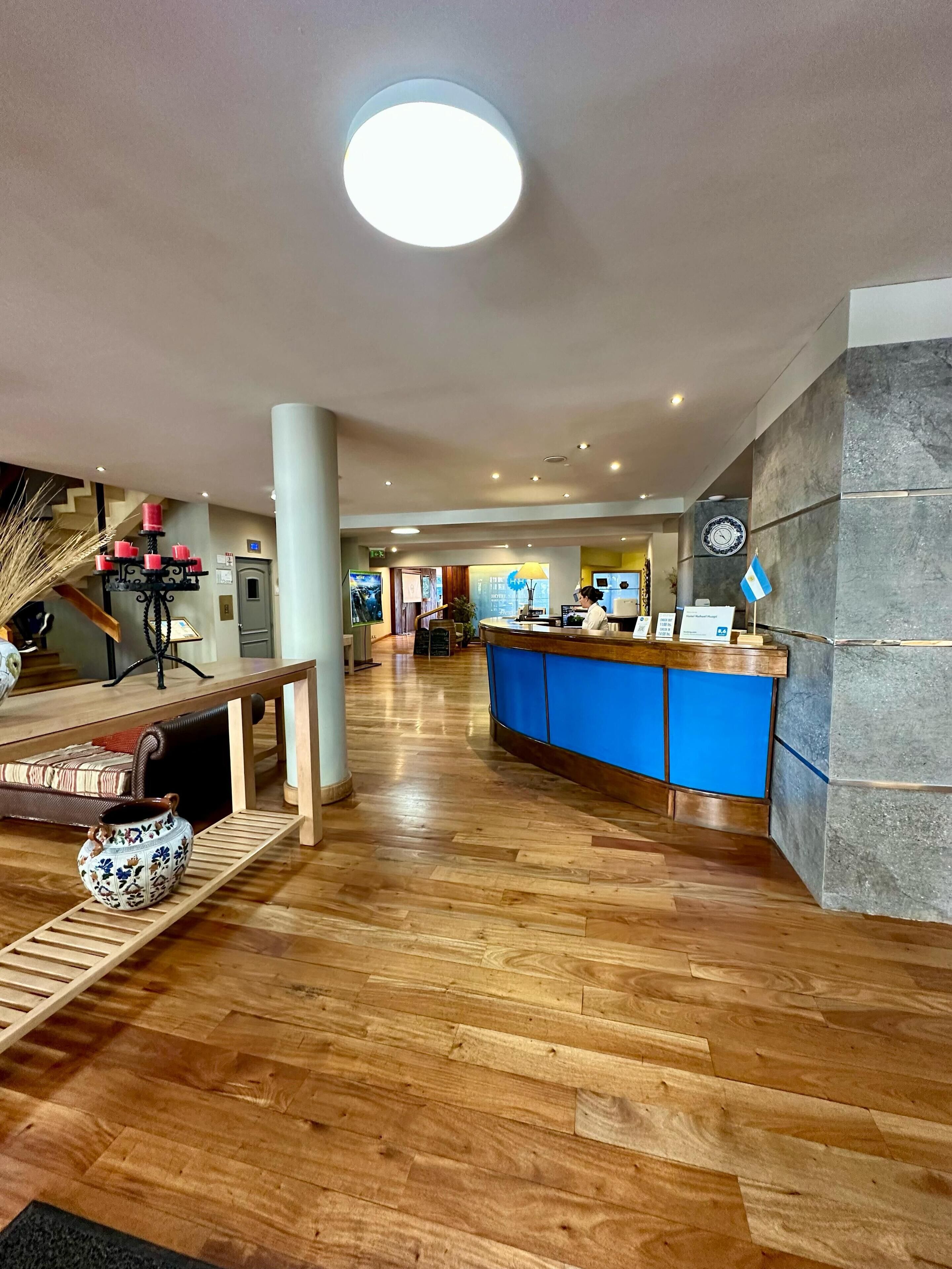 Een ruime lobby met een houten vloer, een receptiebalie en een trap.