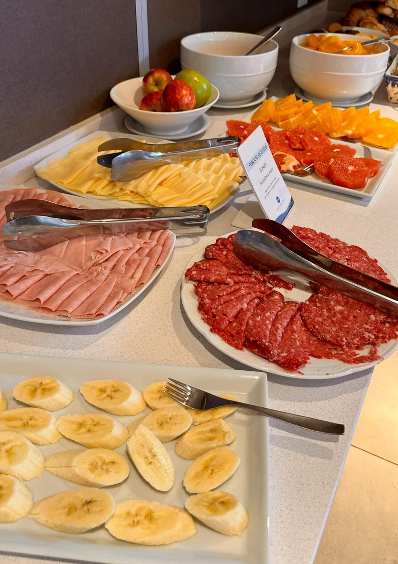 Ein Buffet mit verschiedenen Speisen, darunter Bananenscheiben, Schinken und Wurst.