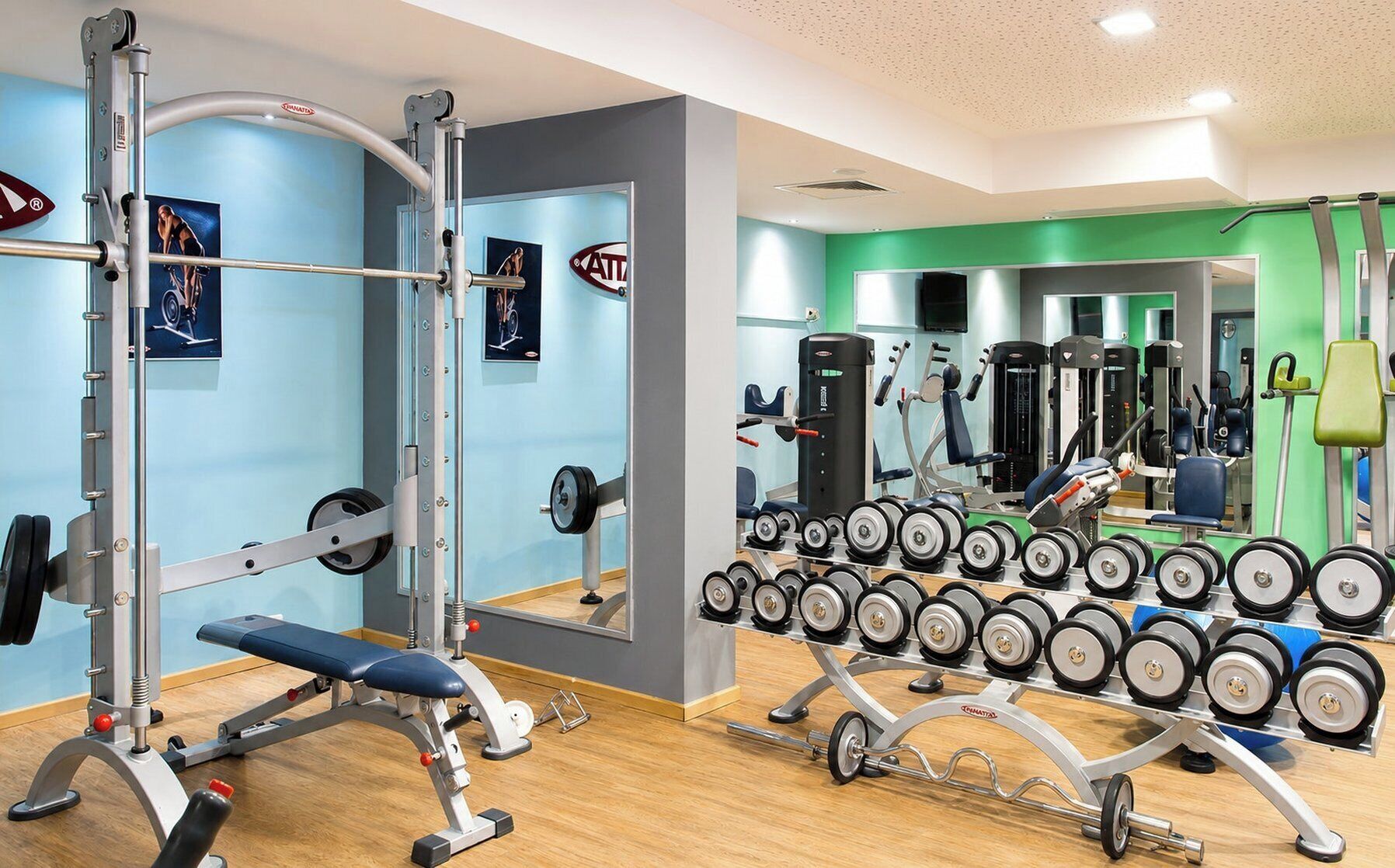 Un gimnasio con equipo de levantamiento de pesas, mancuernas y máquinas de ejercicio.