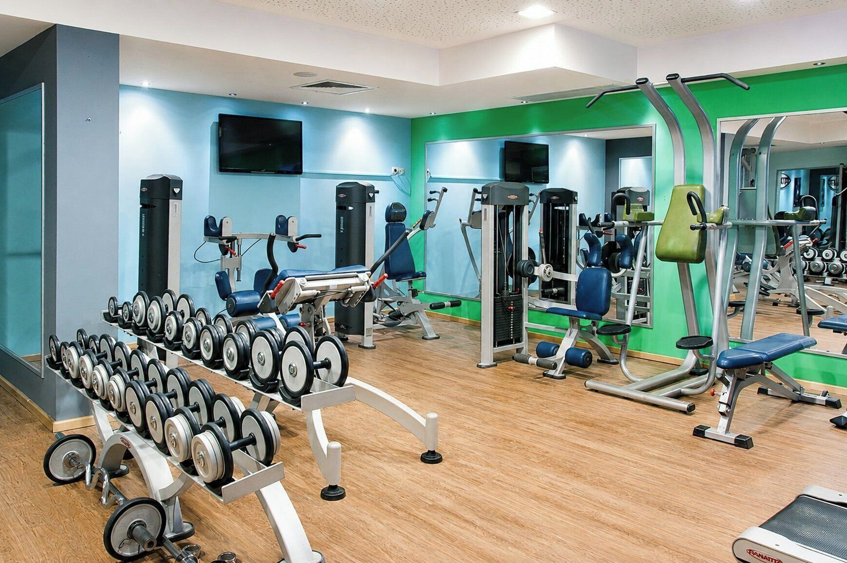Academia com diversos equipamentos de ginástica, incluindo halteres, aparelhos de musculação e esteiras.