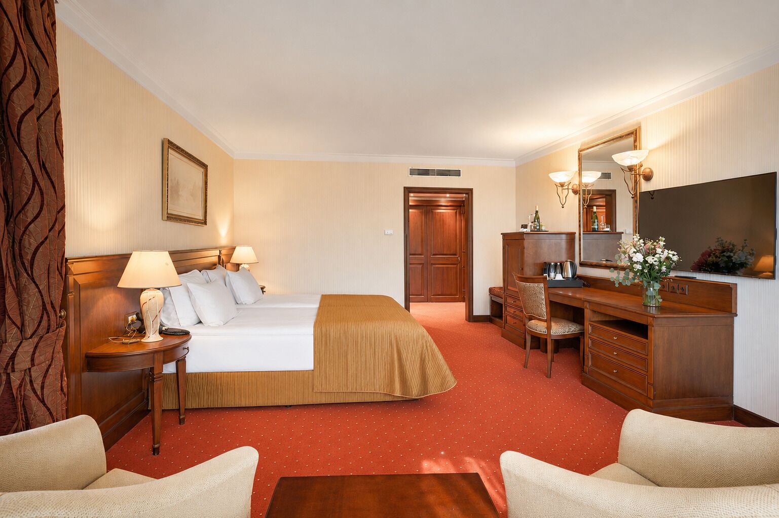 A hotel room with a bed, desk, chair, and a mirror.