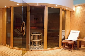 Una sauna con paredes de madera, una puerta de cristal y un banco de madera.