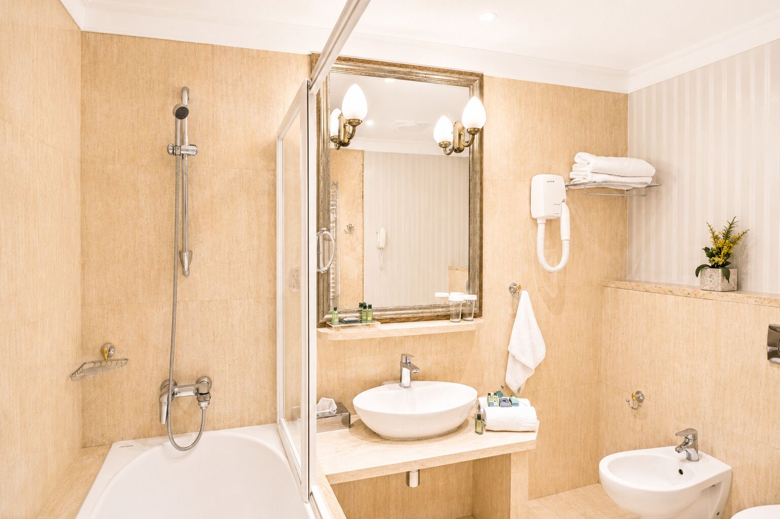 Un baño con bañera, lavabo, espejo, toallero y teléfono.