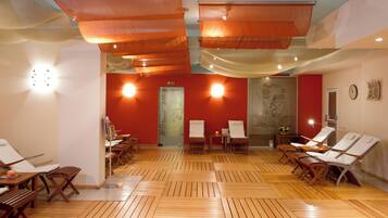 A spa room with wooden flooring, multiple sun loungers, and a large window with a view.