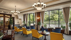 A hotel lobby with yellow and blue seating, large windows, and a chandelier.