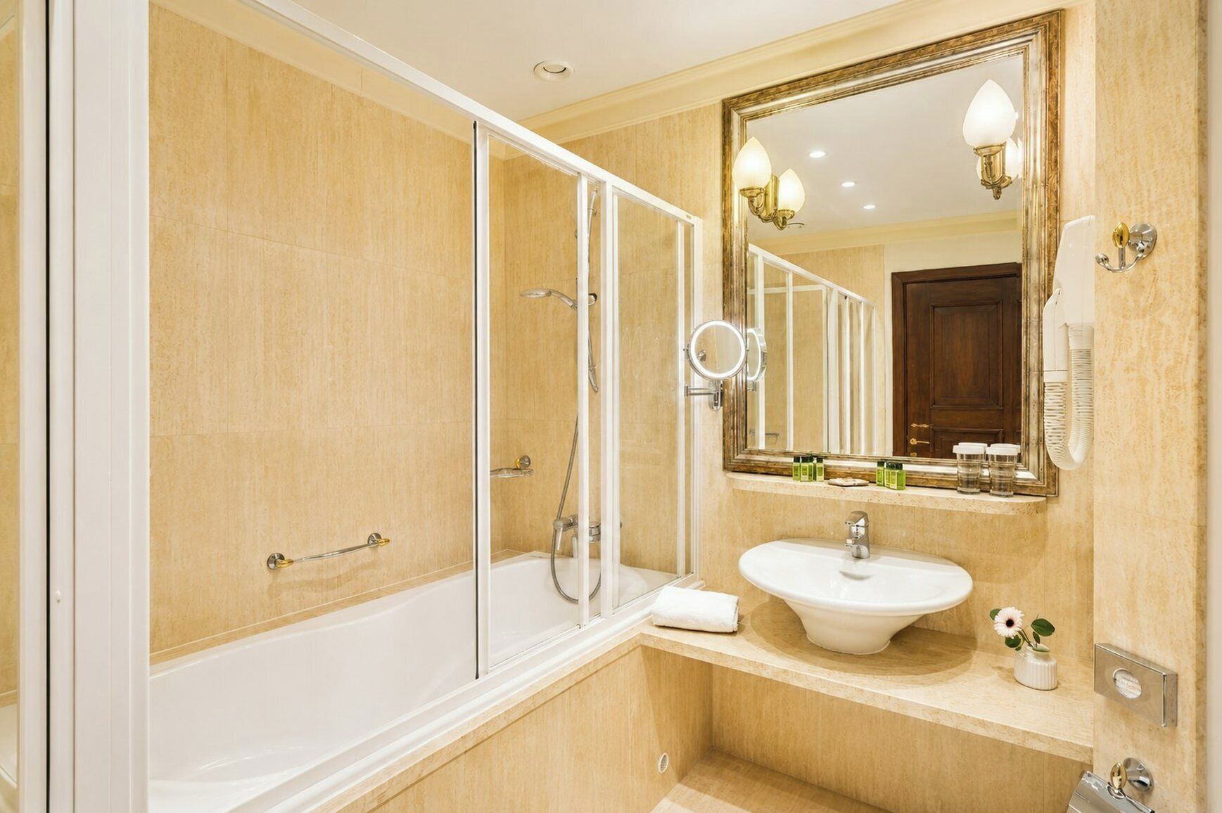 Une salle de bain moderne équipée d’une baignoire, d’un lavabo, d’un grand miroir et d’une cabine de douche.