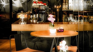 A bar area with a coffee machine, a glass display case, and a potted orchid on the counter.
