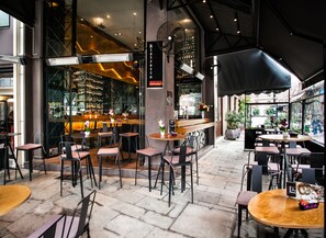 Un restaurante con terraza, zona de bar y vistas a la calle.
