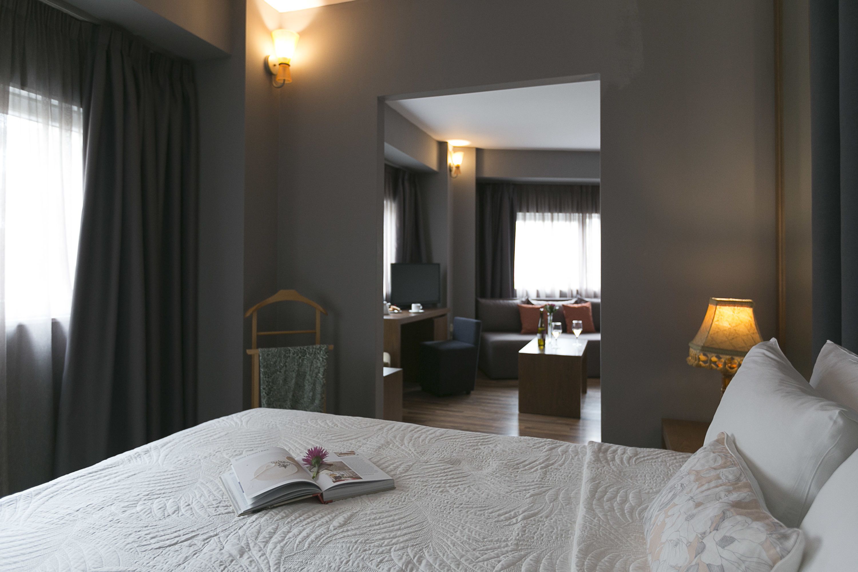 A hotel room with a large bed, a desk, a television, and a dining area.