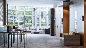 A spacious room with large windows, a dining area with a table and chairs, and a seating area with sofas.