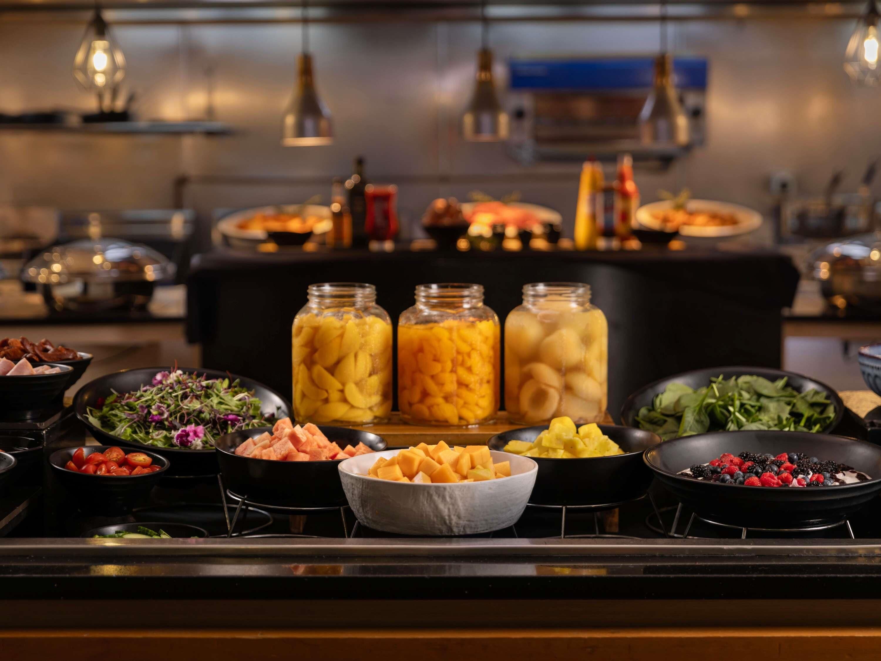A buffet with various food items including salads, fruits, and meats.