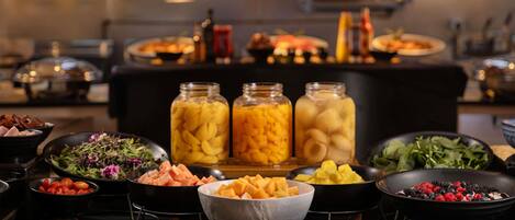 A buffet with various food items including salads, fruits, and meats.