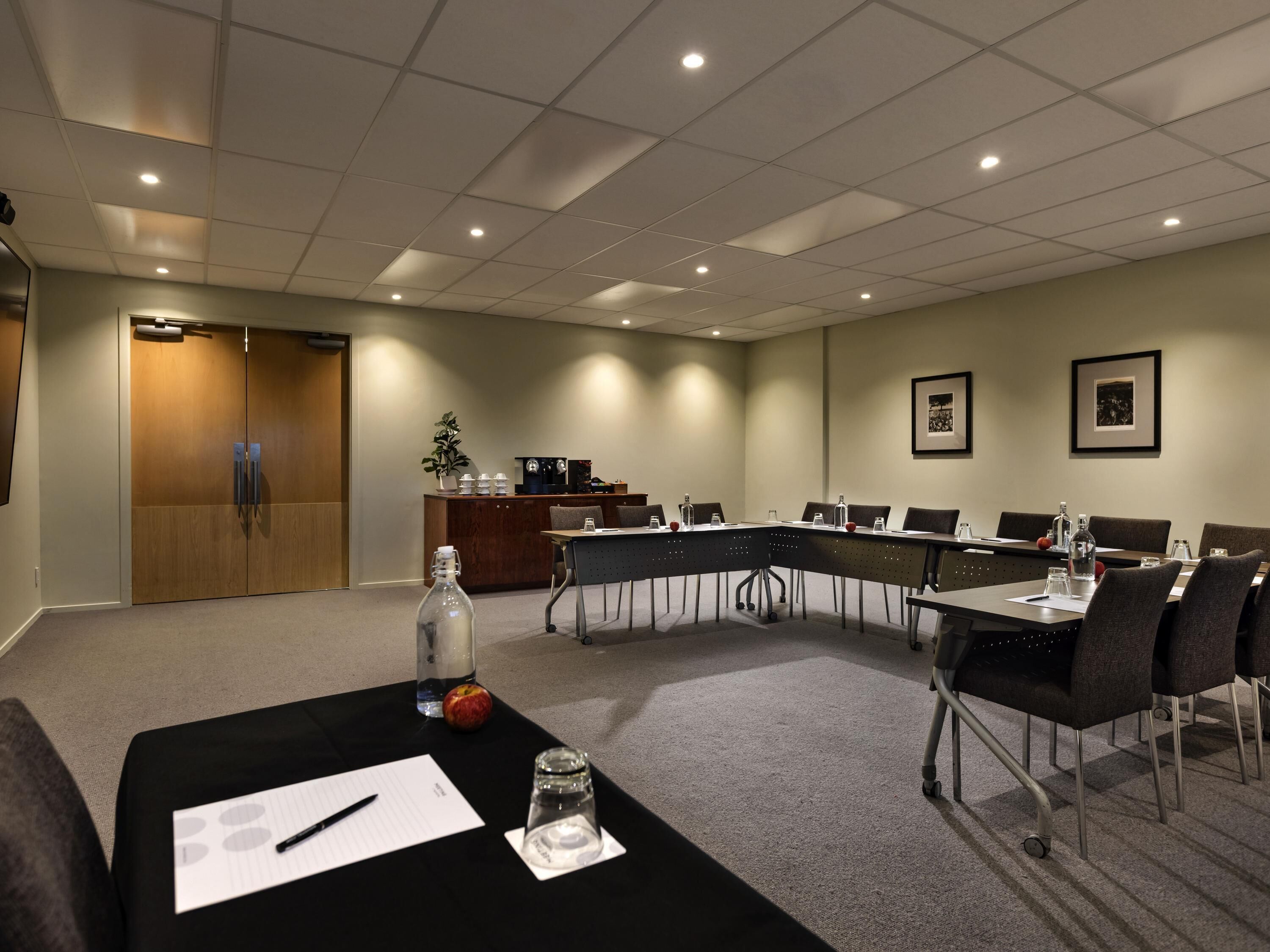 Une salle de conférence équipée d’une longue table, de chaises, d’un coin café et d ’un comptoir d’accueil.