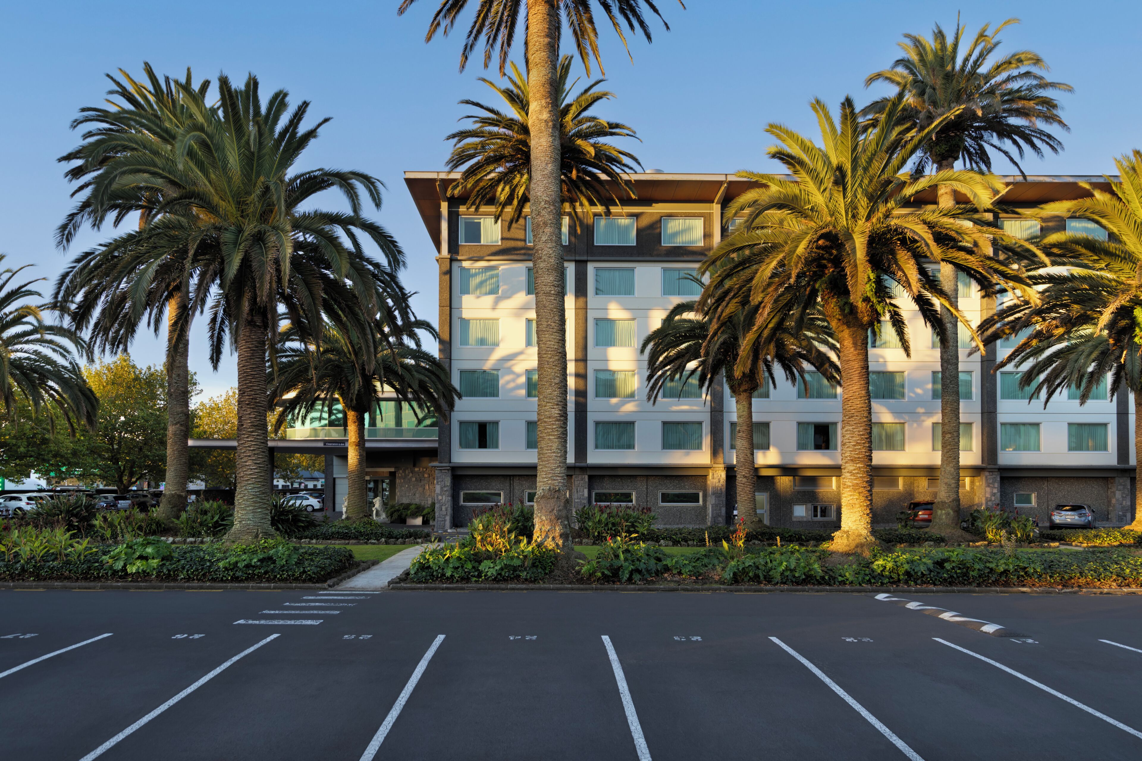 Un hôtel à plusieurs étages au design moderne, avec un parking situé à l’avant.