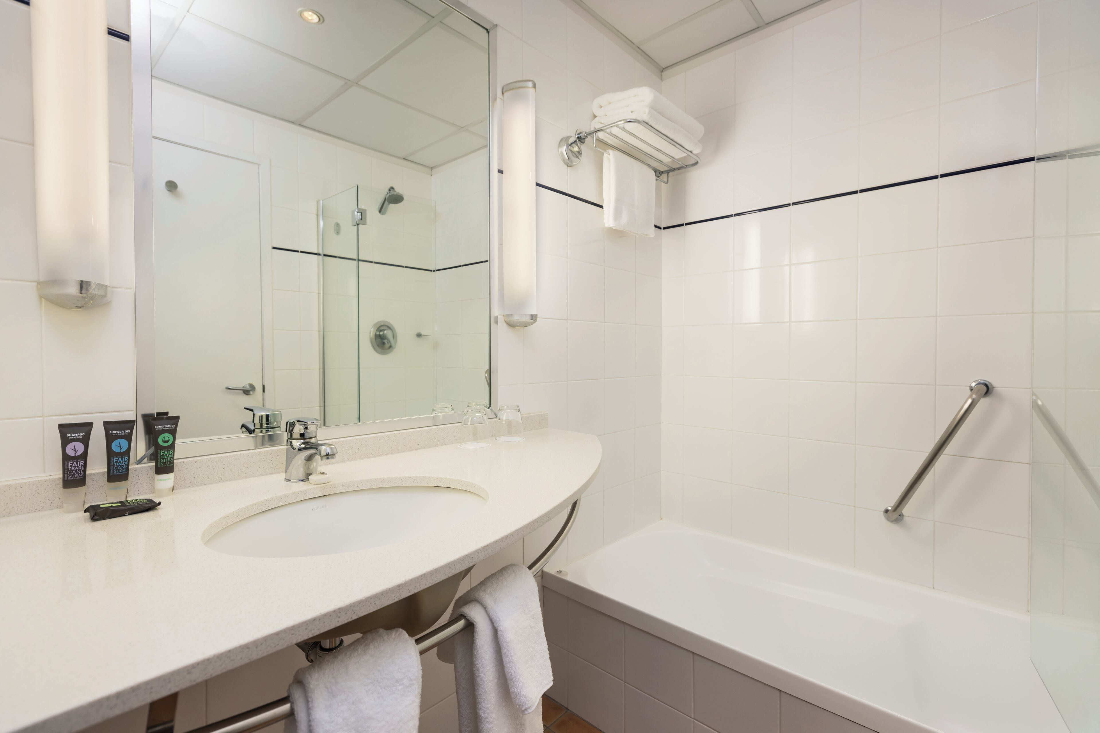 Een moderne badkamer met een grote spiegel, een wastafel, een bad en een douche.