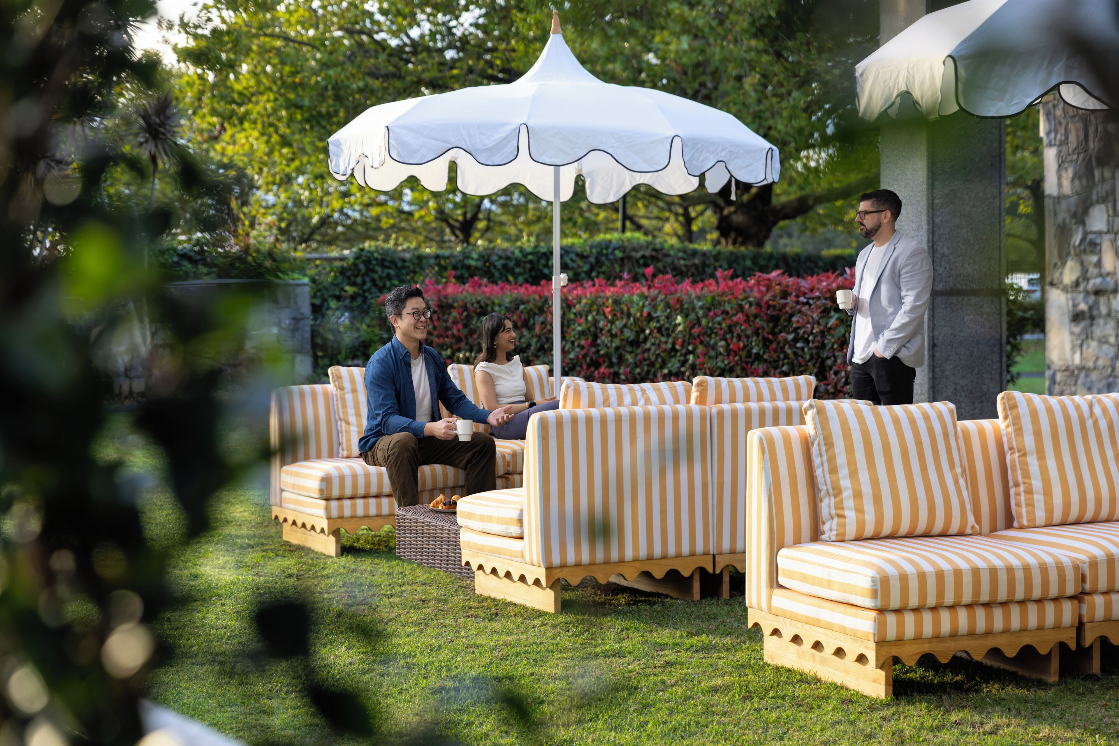 A garden setting with outdoor seating, a white umbrella, and a stone structure.