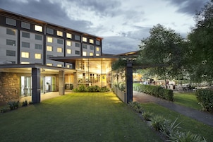 Un hotel moderno con un césped bien cuidado, zona de estar al aire libre y fachada de vidrio.
