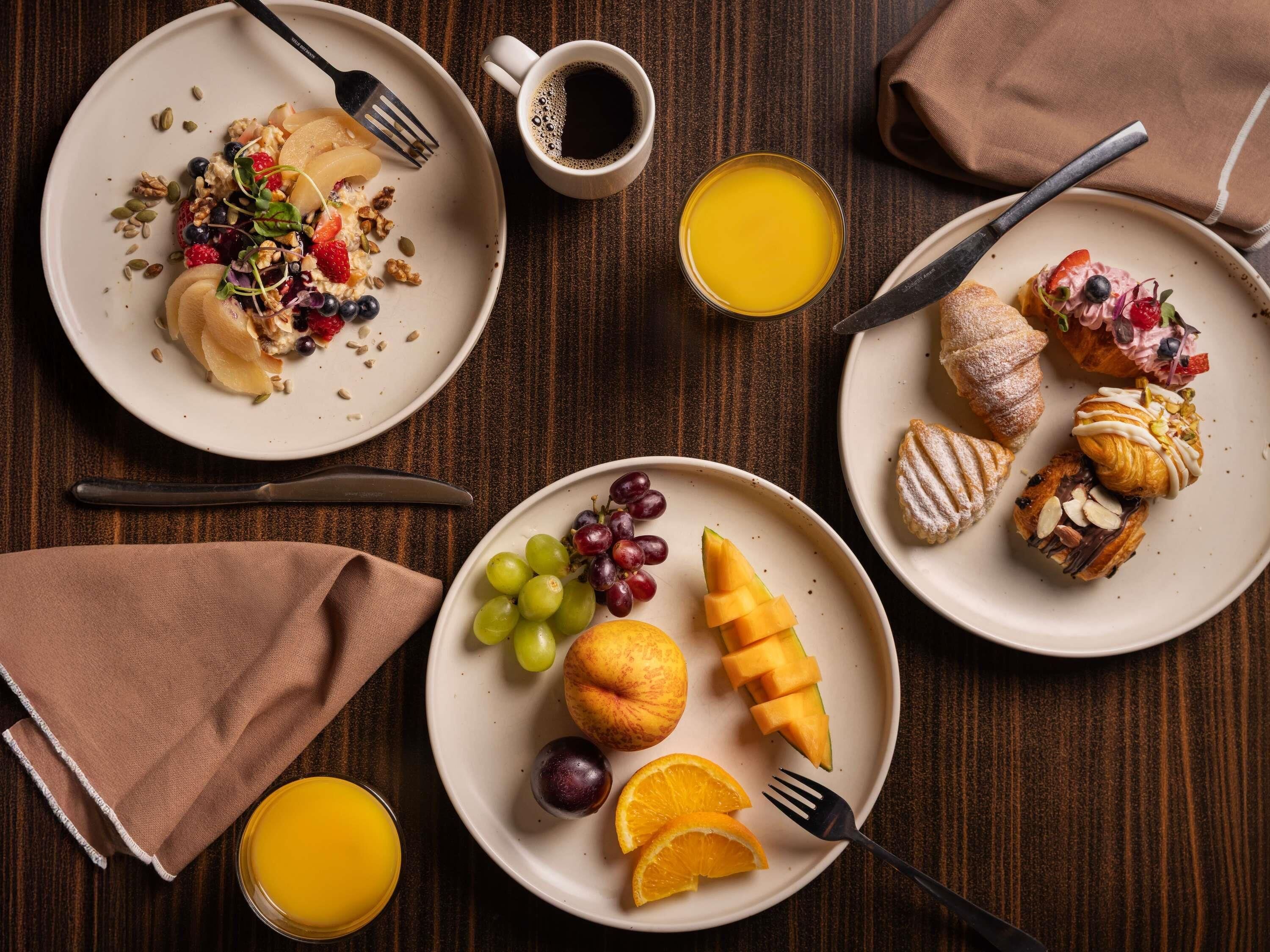 A breakfast setting with plates of food, a coffee cup, and a glass of orange juice on a wooden table.