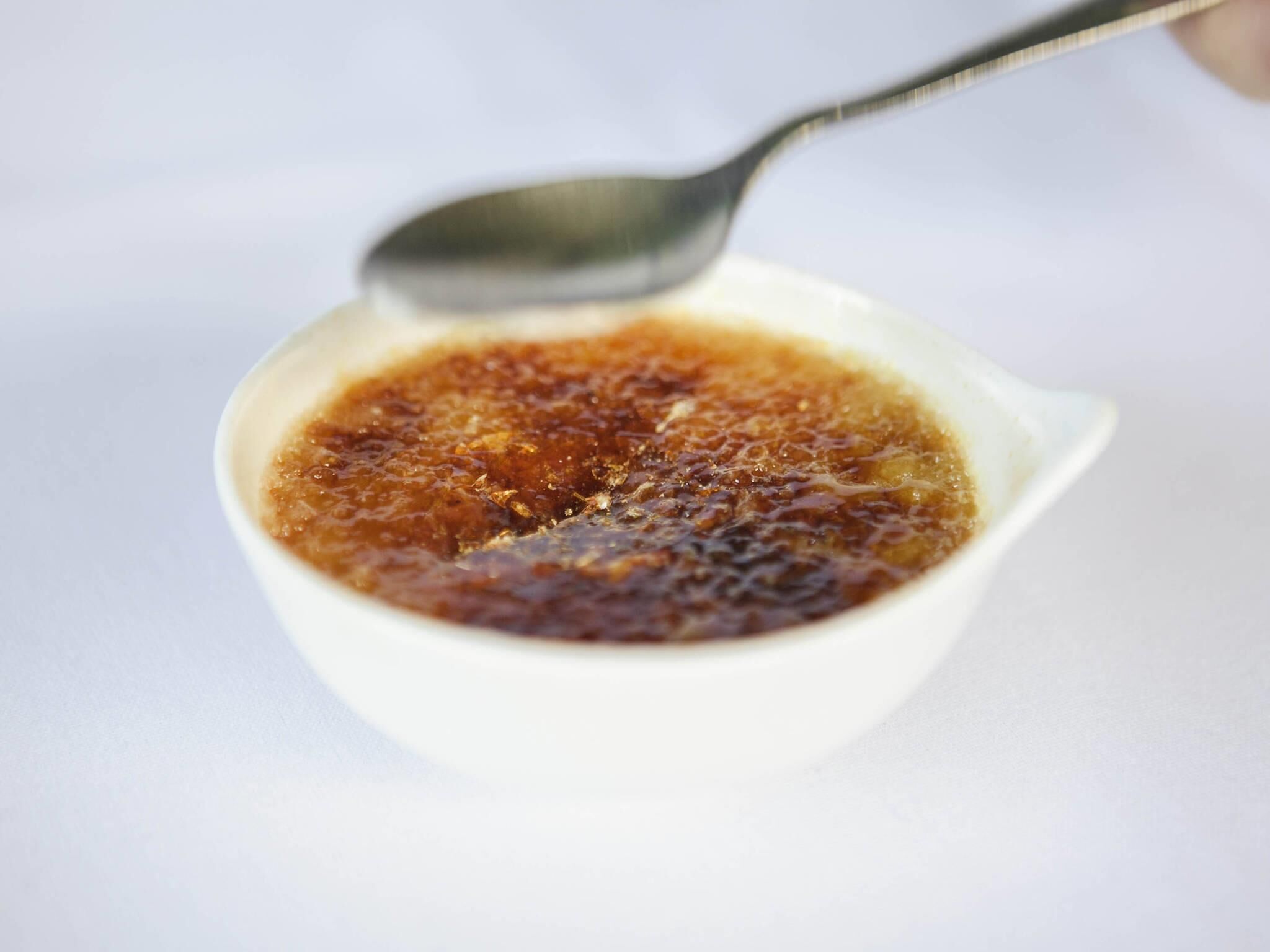 A white bowl containing a dark brown liquid with a spoon.