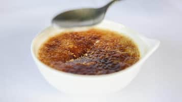 A white bowl containing a dark brown liquid with a spoon.