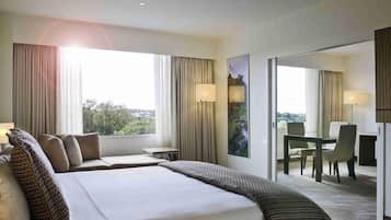 Habitación de hotel con una cama grande, un escritorio, una silla y vistas al exterior.