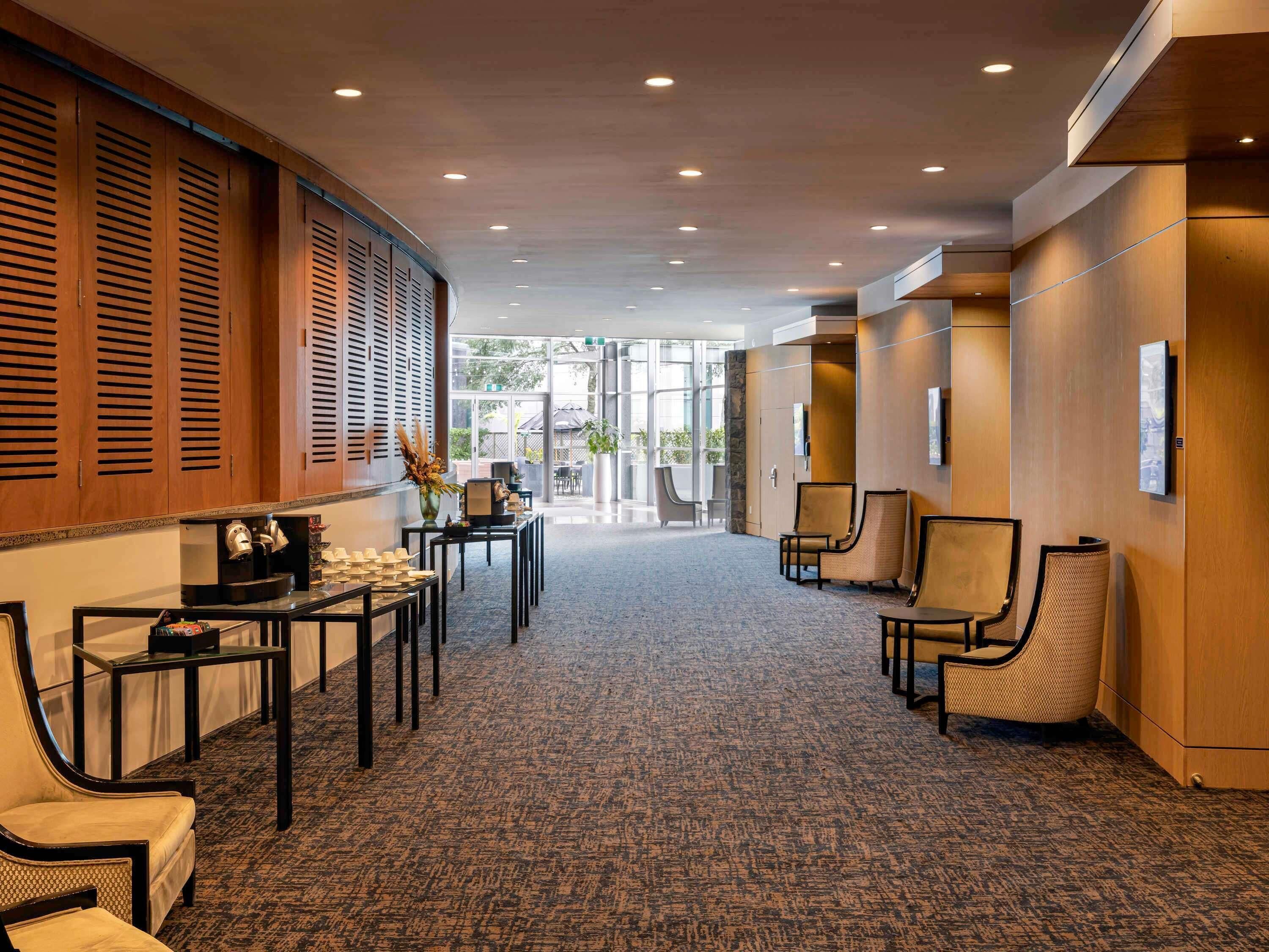 A hotel lobby with a carpeted floor, wooden paneling, and seating areas.