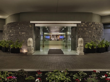 A hotel entrance with stone walls, a reception desk, and potted plants.. Novotel Auckland Ellerslie
