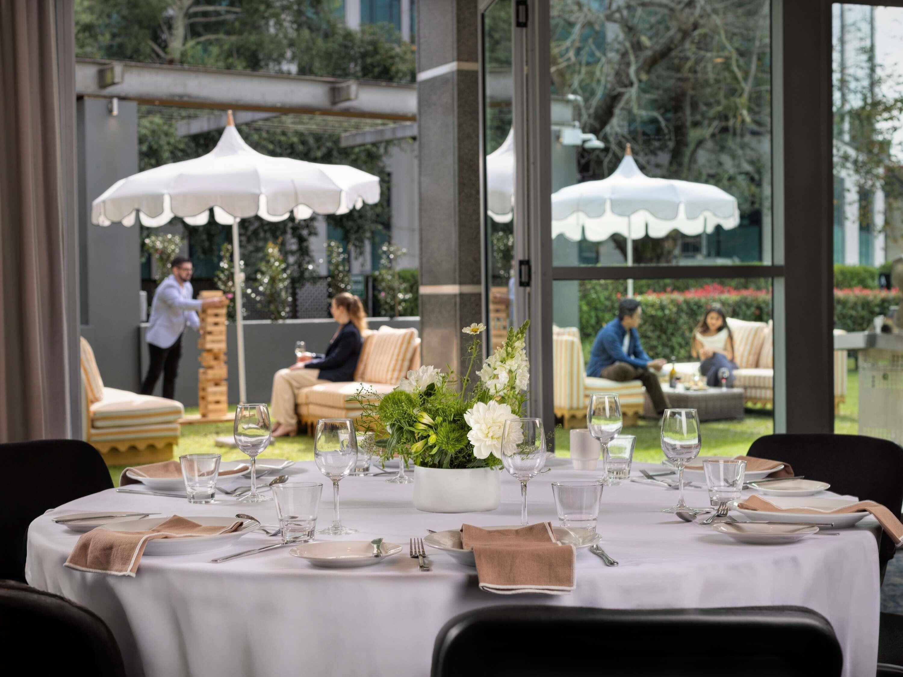 A dining area with tables set for service, outdoor seating, and umbrellas.