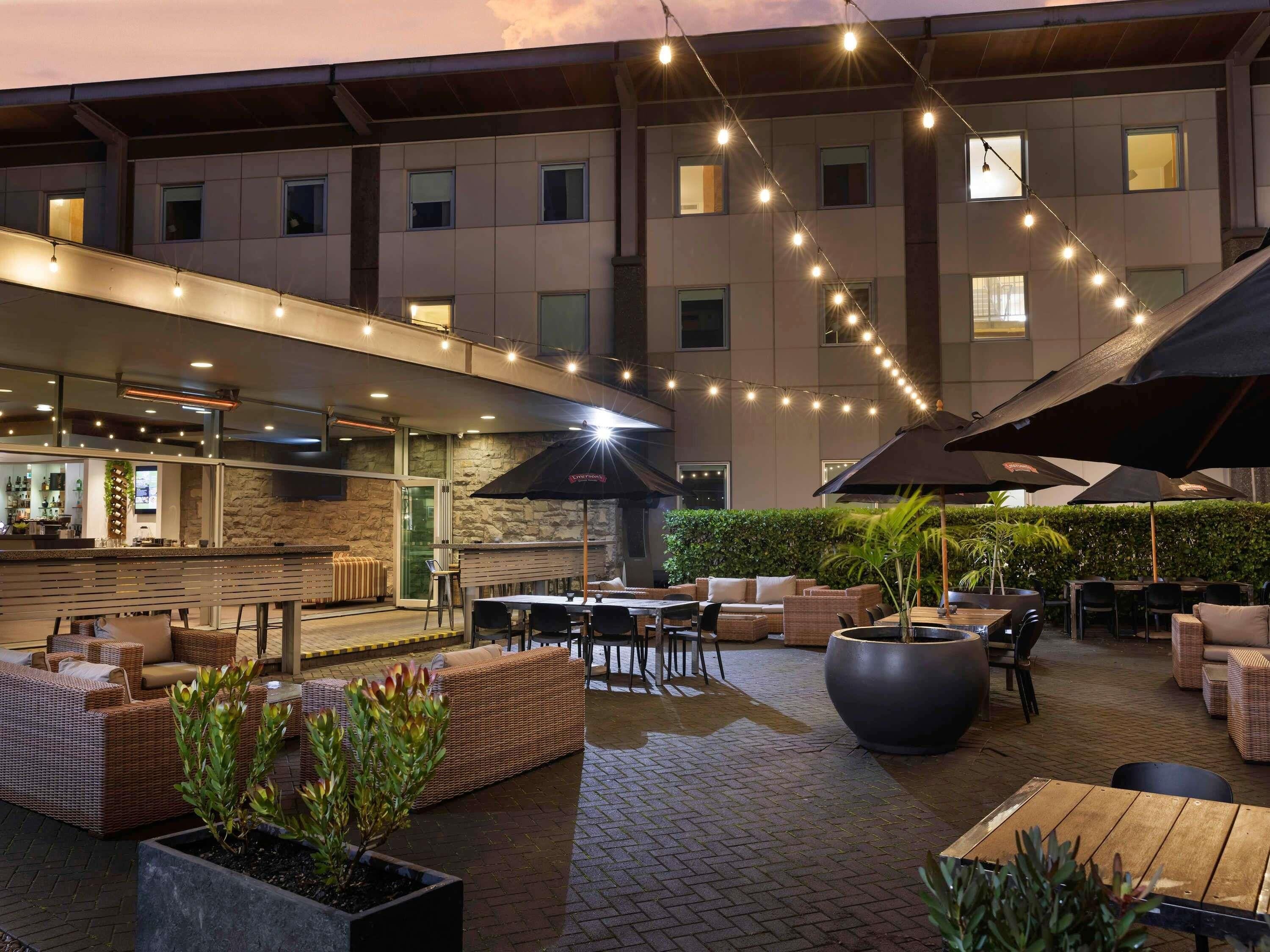 Un espacio de patio al aire libre con asientos, una barra y luces colgantes.