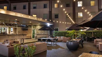Un espacio de patio al aire libre con asientos, una barra y luces colgantes.