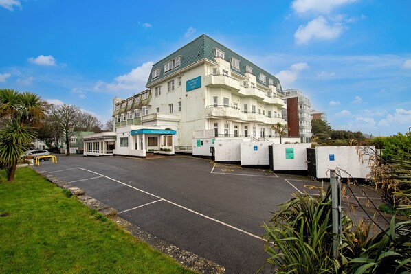 Ein mehrstöckiges Hotel mit Gründach, Parkplatz und einem Gebäude mit der Aufschrift 'Hotel'.